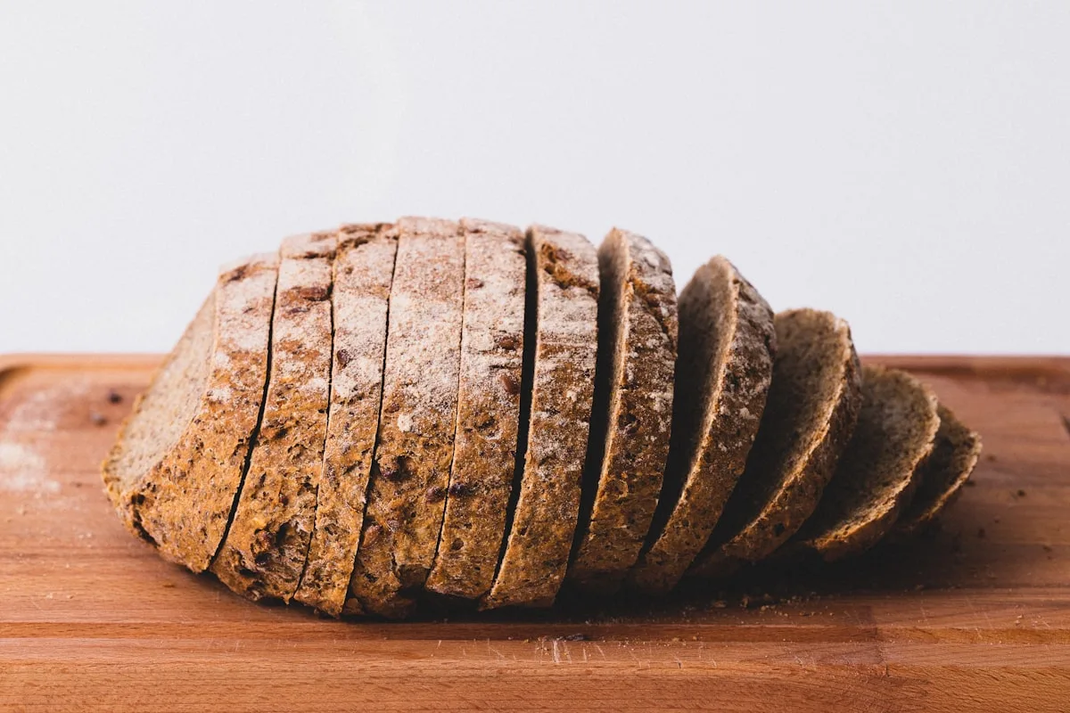 A whole-grain loaf sliced and fanned out on a wooden board
