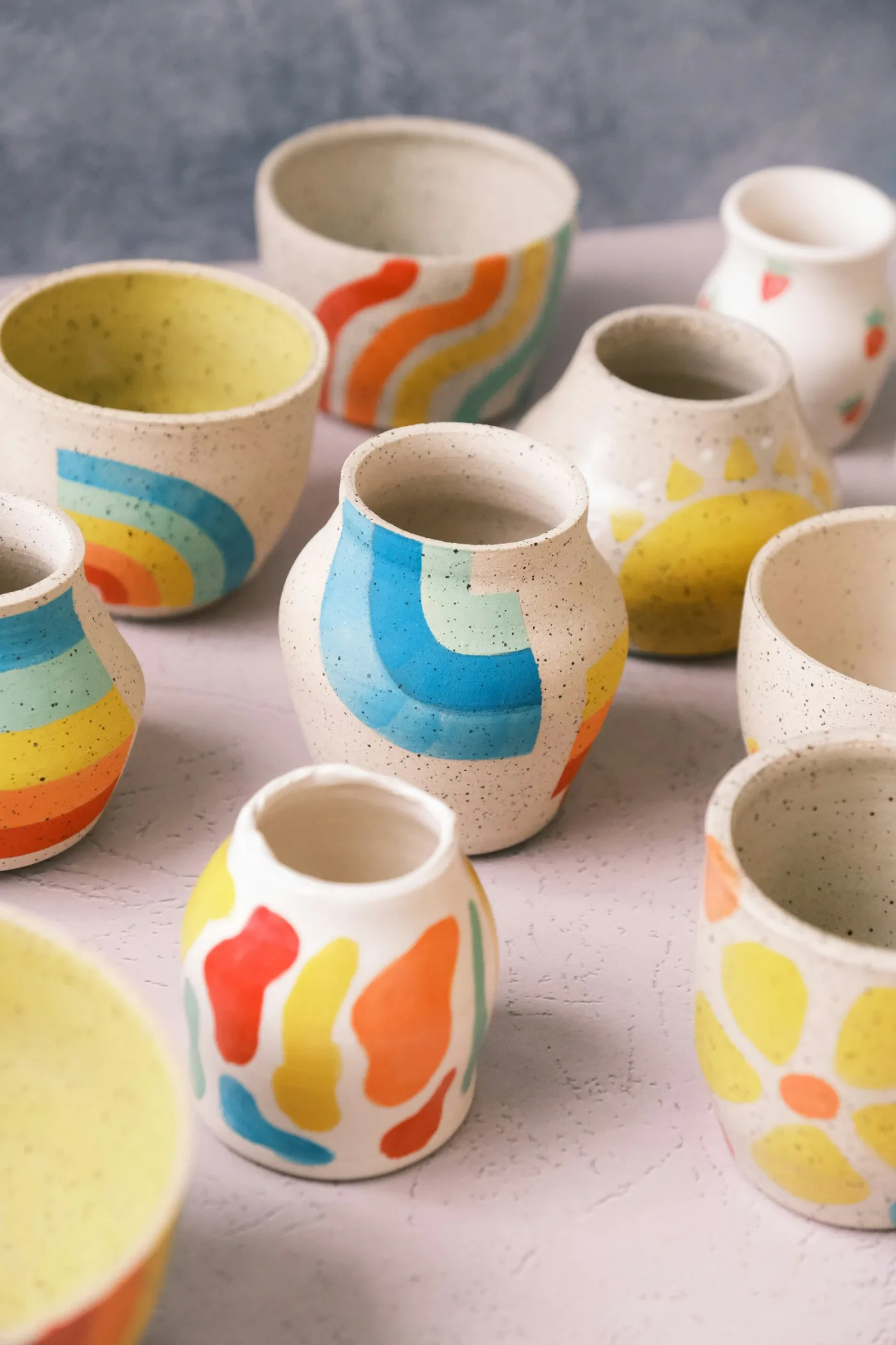 Hand-painted speckled cups and bowls grouped on a pale table