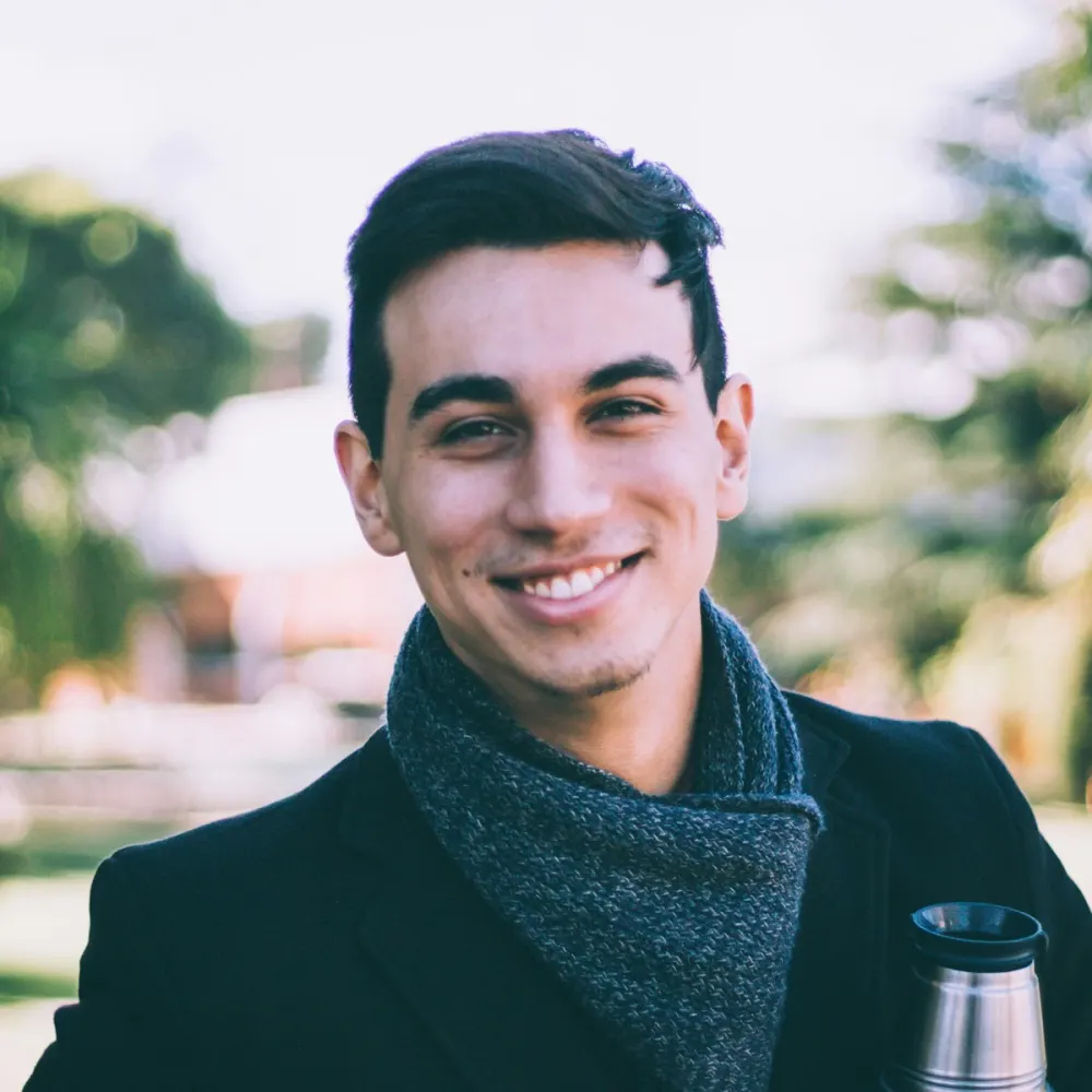 Outdoor portrait of a smiling man in a dark coat and scarf