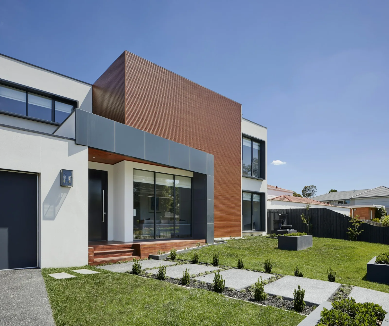 White rendered house with a timber upper storey, paved path across the front lawn